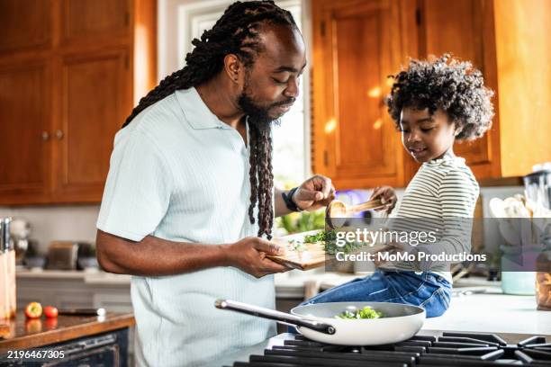father and young daughter cooking together in kitchen - comida sana fotografías e imágenes de stock