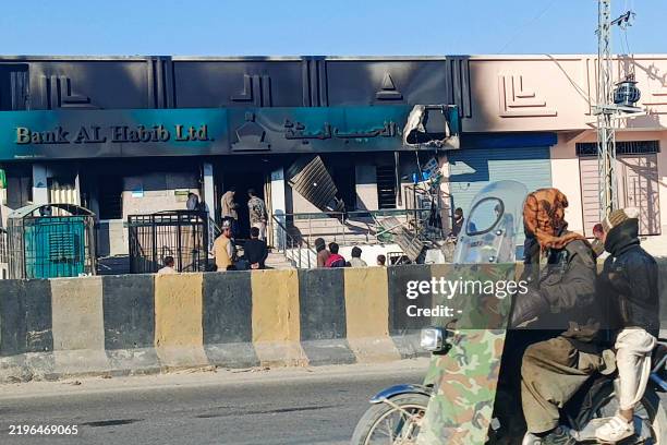 Commuters ride past a bank set ablaze by militants at Kalat district, in Pakistan's Balochistan province on February 1, 2025. Eighteen paramilitaries...