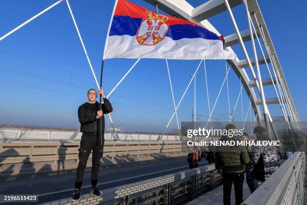 Man holds a Serbian national flag as students and citizens block one of the bridges in Novi Sad on February 1 during the demonstration organised for...