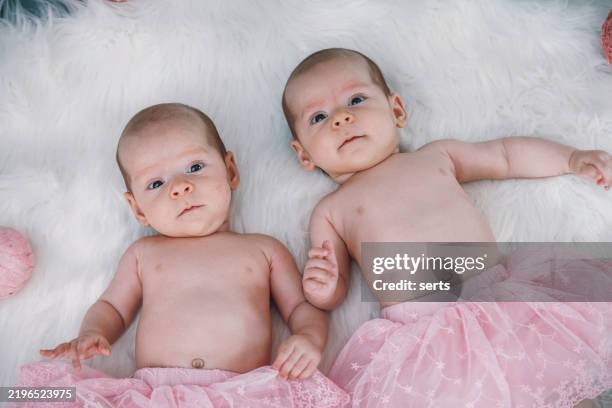 twin baby girls holding hands in pink tutu skirts - cloth nappy stock pictures, royalty-free photos & images