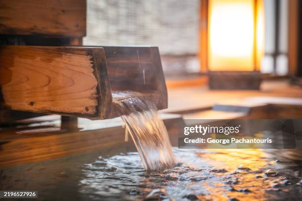 wooden spout pours water into onsen bath - établissement de cure photos et images de collection