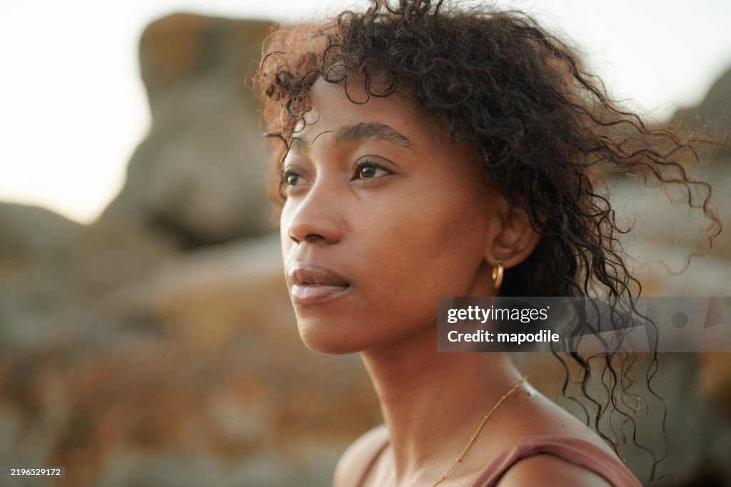 Young black woman with windswept hair posing outdoors under natural light