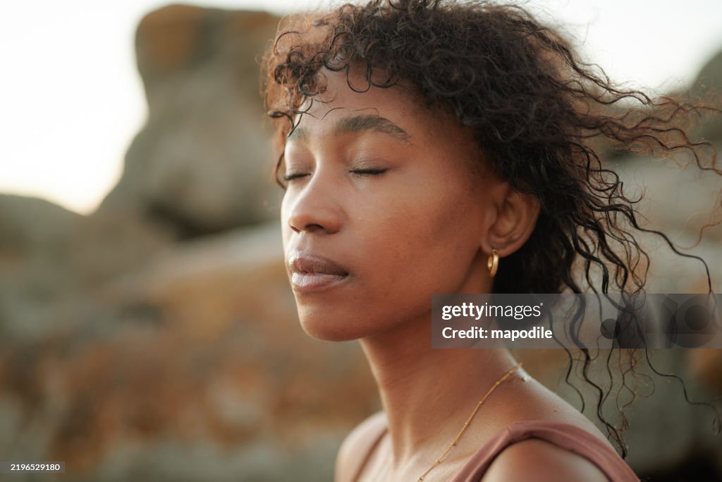 Ruhiges Schönheitsporträt einer jungen schwarzen Frau, die mit geschlossenen Augen der Sonne zuschaut