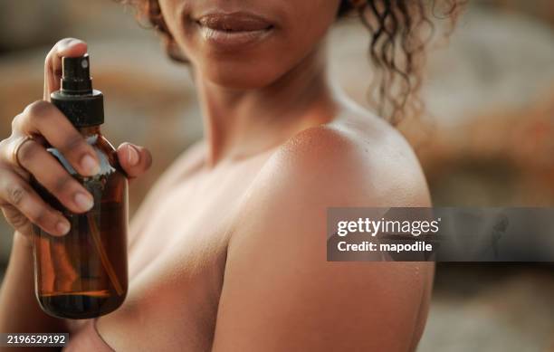 close-up of a black woman applying a moisturising skin care product spray - spray bottle stock pictures, royalty-free photos & images