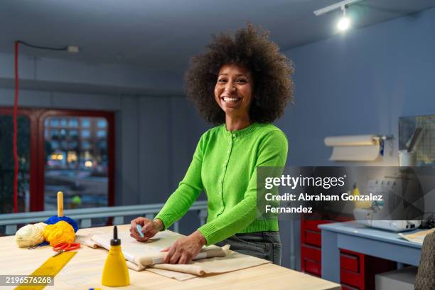 skilled craftswoman stretching canvas, smiling while working in sunlit artisan workspace - afro hairstyle stock pictures, royalty-free photos & images
