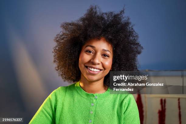 confident young woman with curly hair smiling warmly, expressing genuine happiness while looking directly at viewer - cabelo volumoso imagens e fotografias de stock