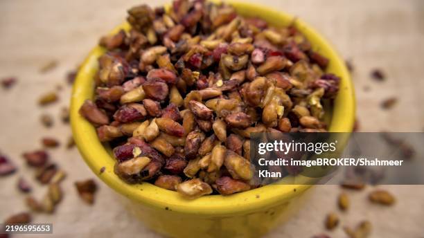 dried pomegranate seeds isolated closeup in a yellow bowl on wooden background - pomegranate seed stock pictures, royalty-free photos & images