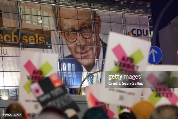 Protesters gather outside the headquarters of the German Christian Democrats , where a banner showing CDU chancellor candidate Friedrich Merz adorns...