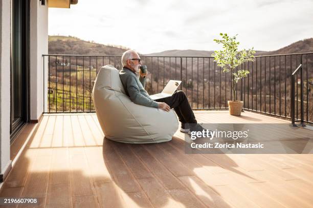 man working remotely with coffee in hand - bean bag stock pictures, royalty-free photos & images