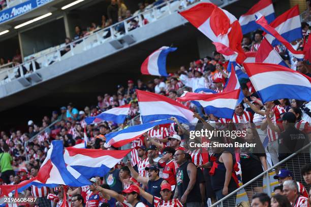 Chivas fans cheer with flags during the 5th round match between Chivas and Queretaro as part of the Torneo Clausura 2025 Liga MX at Akron Stadium on...