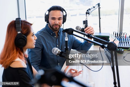 Two podcast hosts recording a show in a studio Two podcast hosts recording a show in a studio
