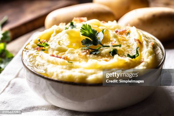 mashed potatoes topped with melted butter, sprinkled with bacon chips and decorated with chopped parsley. - mashed potatoes stock pictures, royalty-free photos & images