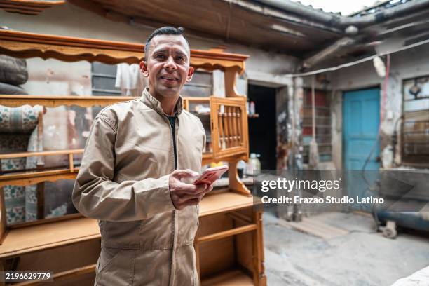 portrait of an amputee carpenter using mobile phone on a woodshop - jumpsuit stock pictures, royalty-free photos & images