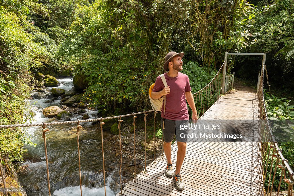 Man enjoying nature walk on a forest bridge