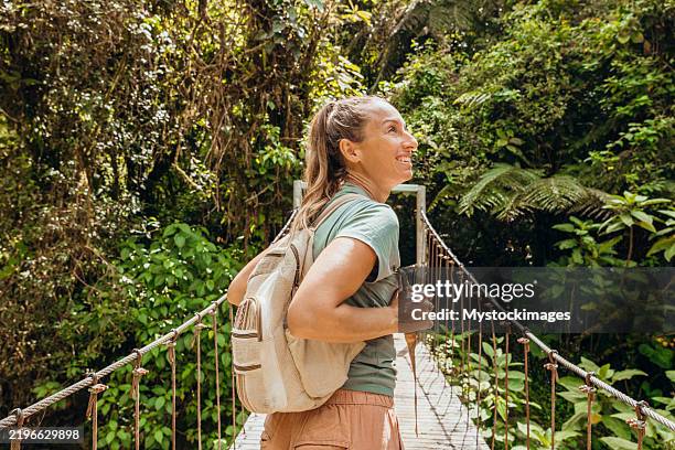 woman hiking across jungle bridge with backpack - central america stock pictures, royalty-free photos & images