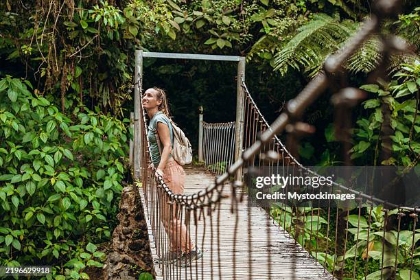 woman exploring jungle suspension bridge - hangbrug stockfoto's en -beelden