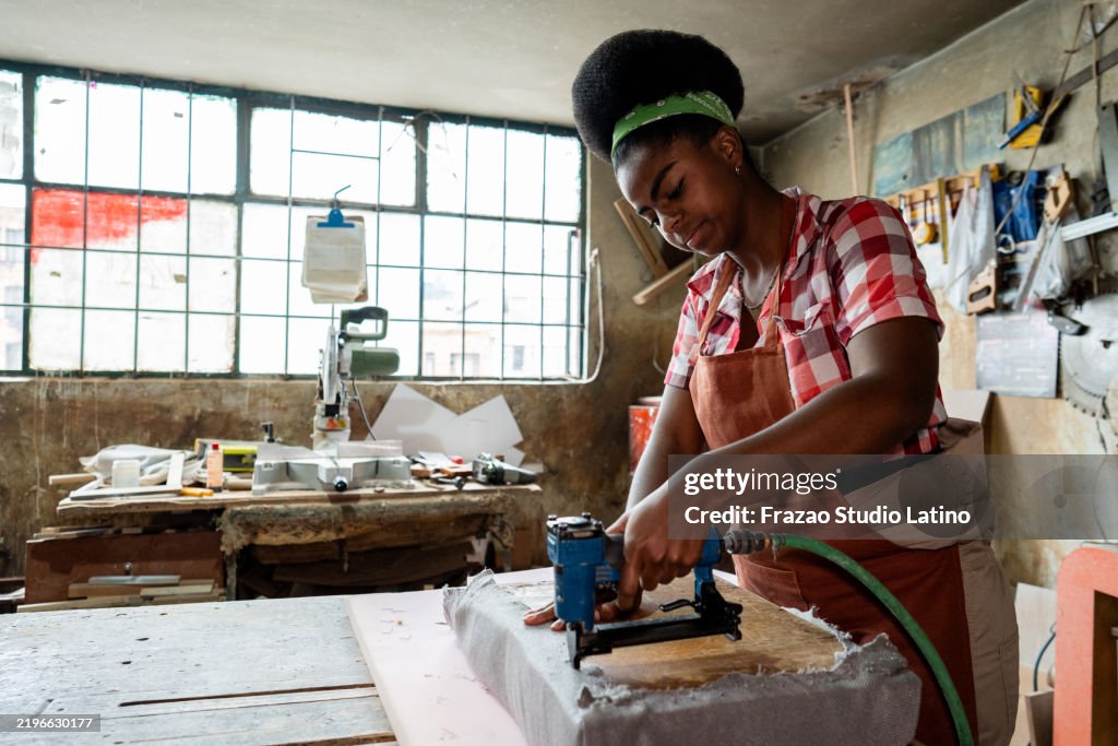 Carpenter stapling an upholstery on a woodshop