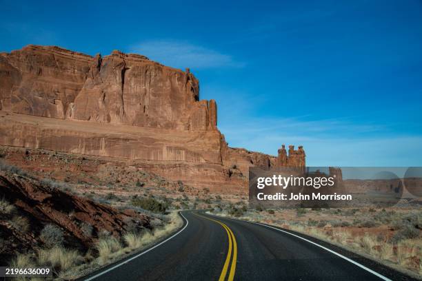 highway through massive sandstone buttes of arches national park, utah, sw usa, north america - canyon stock pictures, royalty-free photos & images