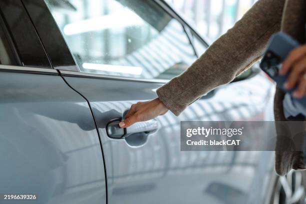 a person unlocking a parked car in a garage close-up - car door stock pictures, royalty-free photos & images