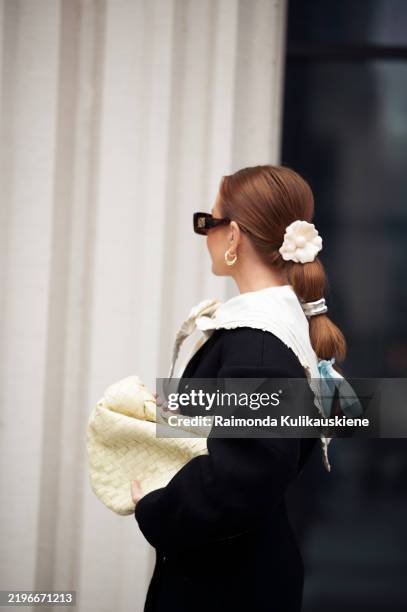 Guest wears black long sleeve dress, white scarf and pale yellow bag outside the Herskind fashion show during the Copenhagen Fashion Week...