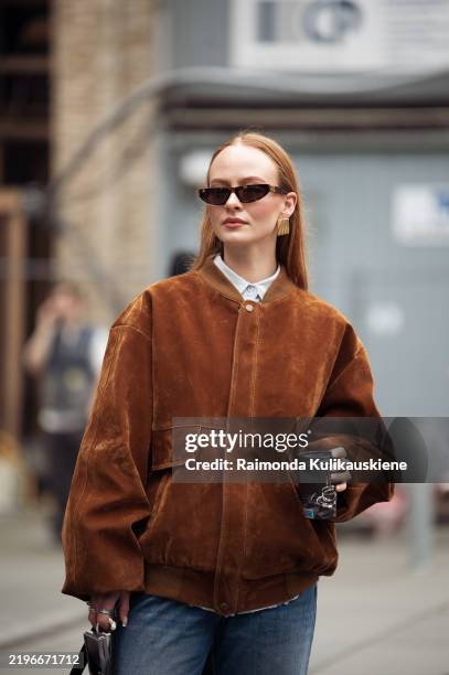 Guest wears blue jeans, brown suede jacket and black bag outside the Herskind fashion show during the Copenhagen Fashion Week Autumn/Winter 2025 on...