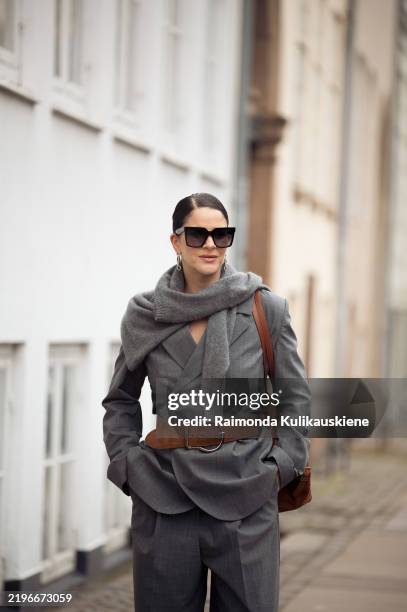 Gili Biegun wears grey suit, brown leather belt, brown bag, sunglasses and grey sweater around her shoulders during the Copenhagen Fashion Week...