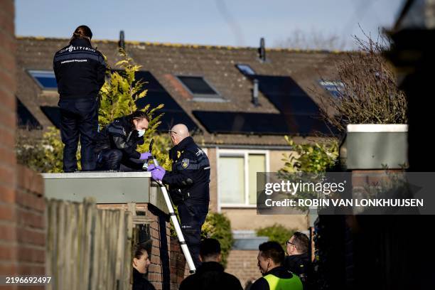 Forensic police officers pick up a knife on the roof of a shed during the investigation at the scene where an 11-year-old girl was stabbed to death...