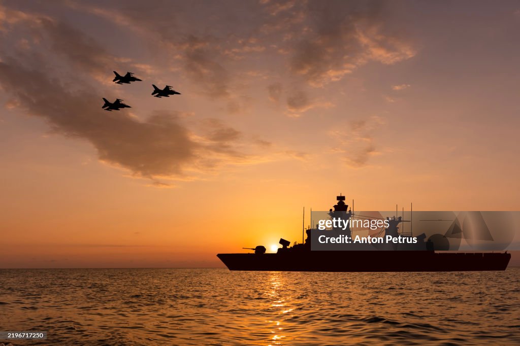 Warship and fighter jets at sunset