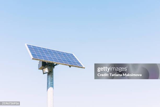 a single solar panel stands and charges a lantern, an eco-friendly concept - sun panels stock pictures, royalty-free photos & images