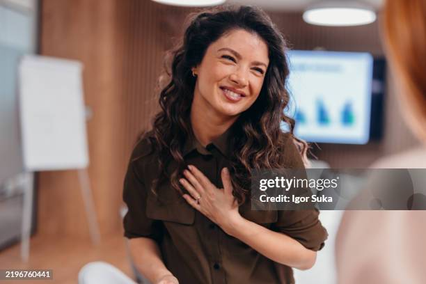 businesswoman laughing with hand on chest during a meeting - hands on chest stock pictures, royalty-free photos & images