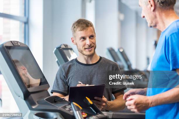 personal trainer explaining senior man exercise plan at rehab - physical therapist stock pictures, royalty-free photos & images