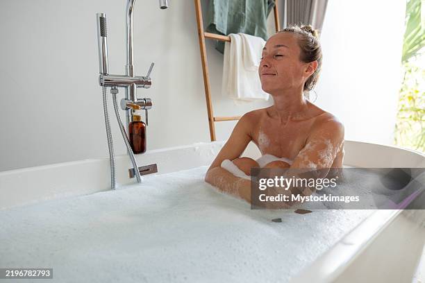 relaxed woman soaking in modern bathroom bathtub - drenched stock pictures, royalty-free photos & images