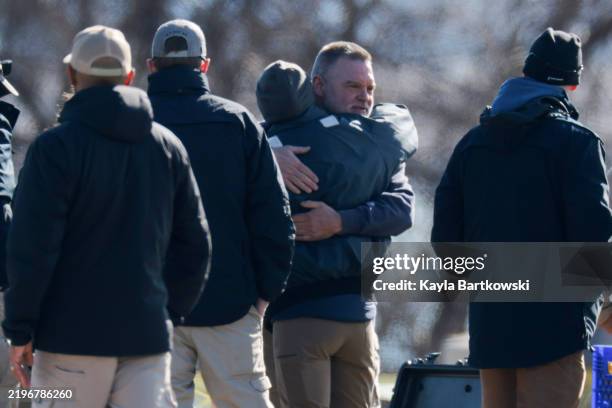 People hug as they setup a staging area for law enforcement to continue their investigation into the American Airlines plane that crashed into the...