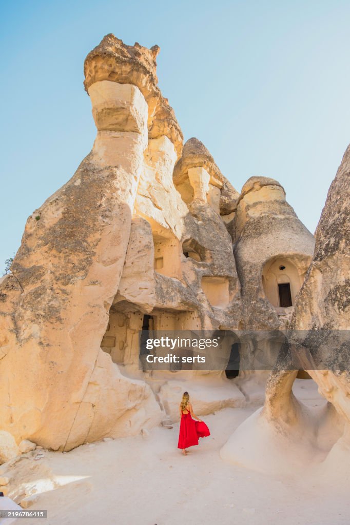 Femme voyageuse en robe rouge explorant les anciennes habitations troglodytes de la vallée de Pasabag, Cappadoce, Turquie