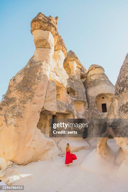 femme voyageuse en robe rouge explorant les anciennes habitations troglodytes de la vallée de pasabag, cappadoce, turquie - cheminée de fée photos et images de collection