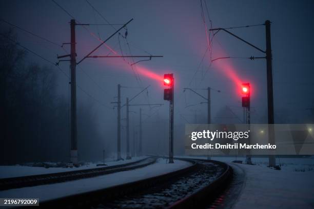 dense fog cloaks rail tracks, saturating air with humidity in winter. red signals glows in snow - semaphore-railway-line stock pictures, royalty-free photos & images