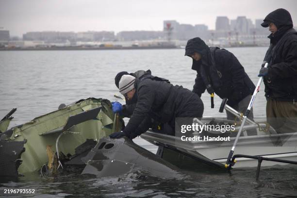 In this handout provided by the National Transporation Safety Board NTSB investigators along with members of the salvage crew recover wreckage from...