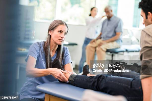 physical therapist examining patient's foot in clinic - sprain stock pictures, royalty-free photos & images