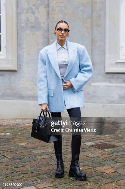 Deimante Kazenaite wears blue oversized jacket, leggings, black Hermes bag, boots outside TG Botanical during the Copenhagen Fashion Week...