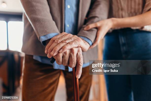 nurse assisting elderly man holding a walking stick - fragility stock pictures, royalty-free photos & images