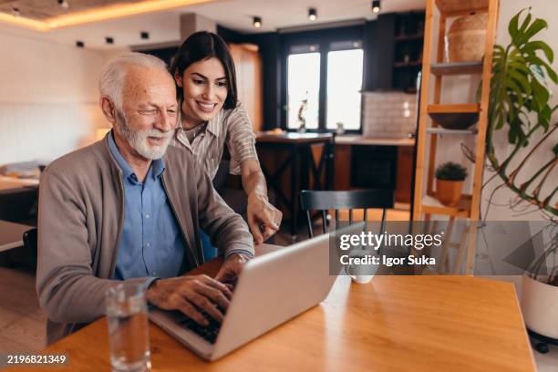 senior man learning how to use laptop with his daughter - tutorial stock pictures, royalty-free photos & images