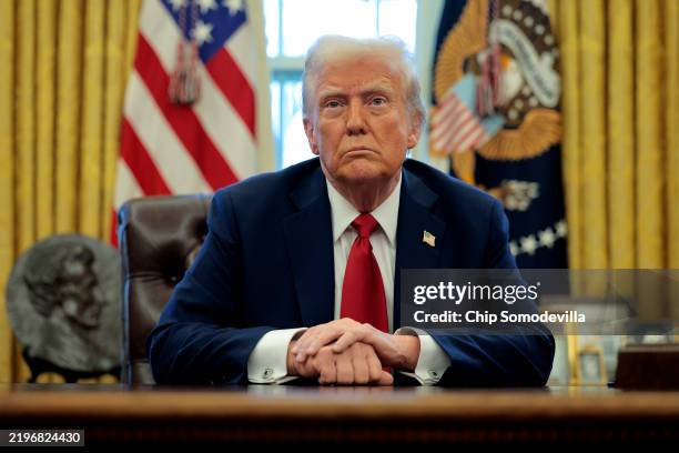 President Donald Trump talks to reporters from the Resolute Desk after signing an executive order to appoint the deputy administrator of the Federal...