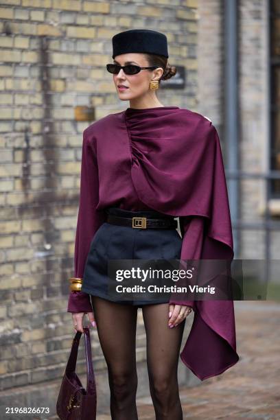Nina Sandbech wears black hat, burgundy wrapped ruffled top, black shorts, tights, YSL bag outside Munthe during the Copenhagen Fashion Week...