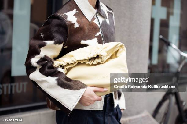 Sophia Geiss wears cow print cropped jacket with a zipper, pale yellow bag, blue wide jeans during the Copenhagen Fashion Week Autumn/Winter 2025 on...