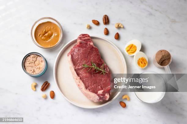 selection of food with high protein content. overhead view of raw steak and other protein rich food. - proteína fotografías e imágenes de stock