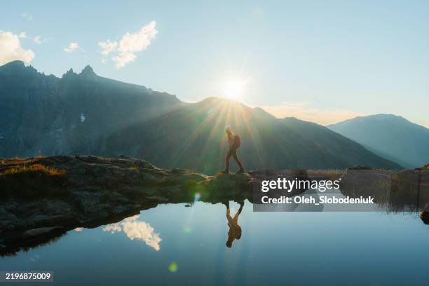 woman hiking near reflection lake in epic mountains - bergen noorwegen stockfoto's en -beelden