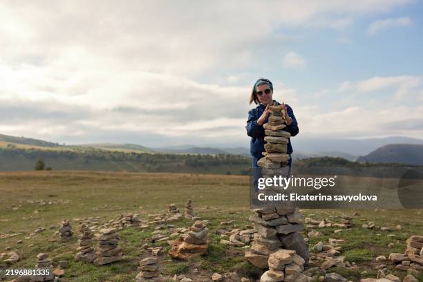 a female tourist puts stones in a pyramid. - stack rock stock pictures, royalty-free photos & images