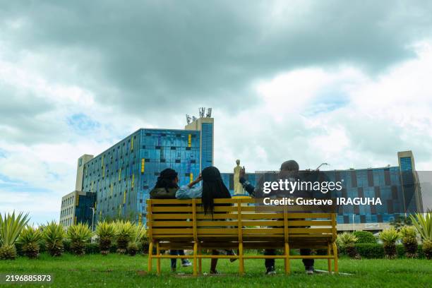 people sitting on a bench in front of modern architecture in kigali, rwanda - rwanda stock pictures, royalty-free photos & images
