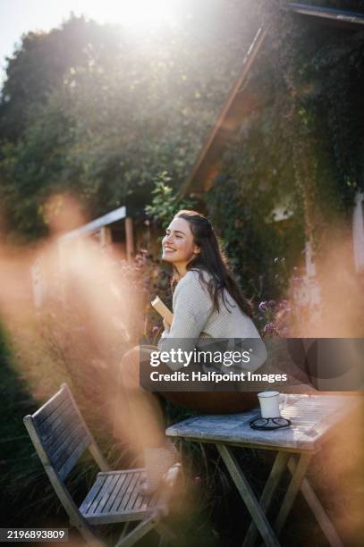 hygge moment. woman sitting outdoors in garden, smiling. single woman enjoying free weekend. - zen-like stock pictures, royalty-free photos & images