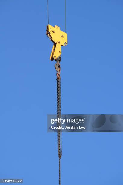 steel chains hanging from a crane hook on a construction site. - hoist stock pictures, royalty-free photos & images